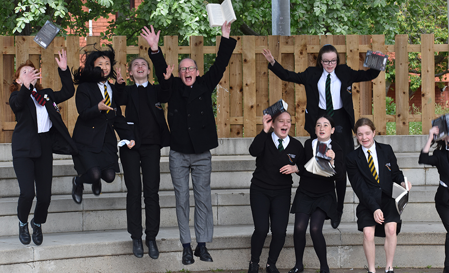 Students and Teacher jumping with books