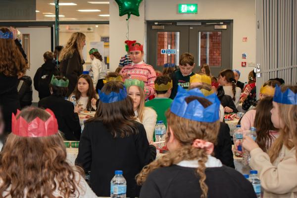 Photo of students enjoying the lunch wearing Christmas jumpers with balloons attached to the tables