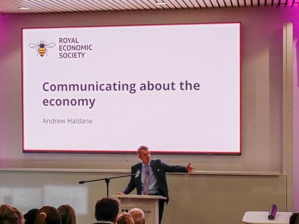 Photo of one of the lecturers giving a presentation in front of seated students